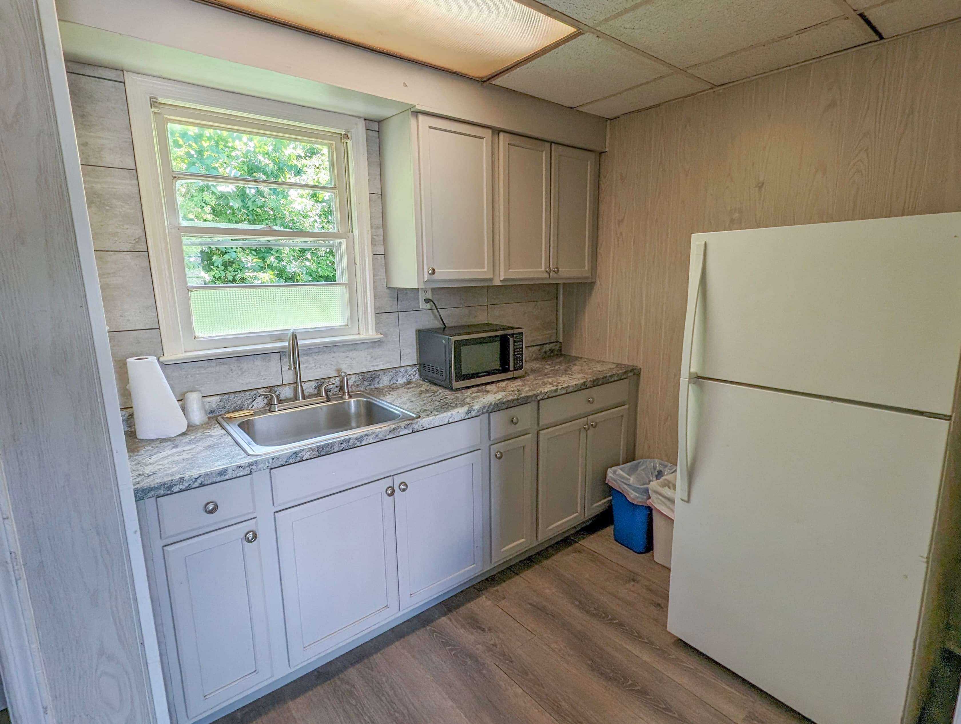 Efficiency kitchenette with white cabinets and full refrigerator